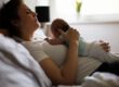 Wochenbett früher und heute: Mutter ruht im Bett mit ihrem Neugeborenen auf der Brust